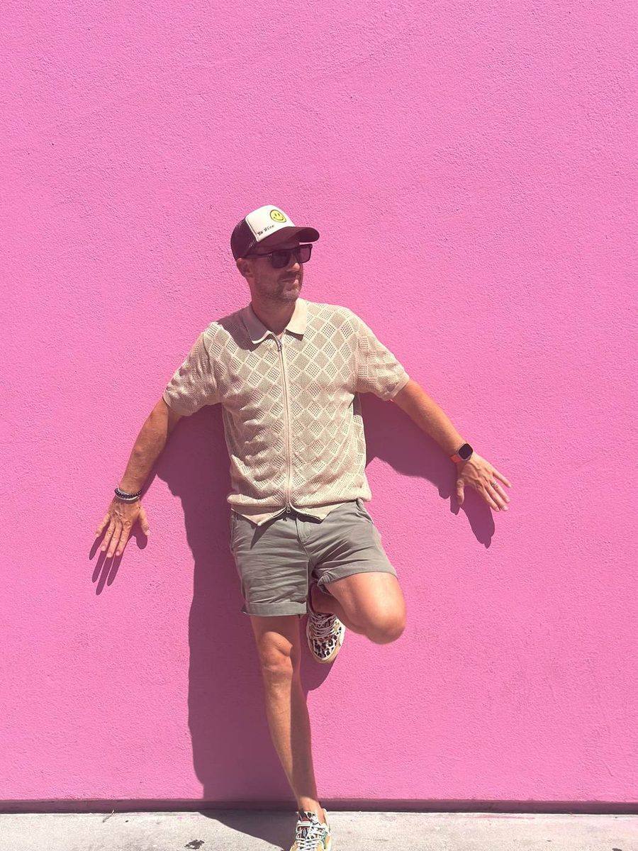 Rew Golding leaning against a bright pink wall on Melrose Avenue, Los Angeles